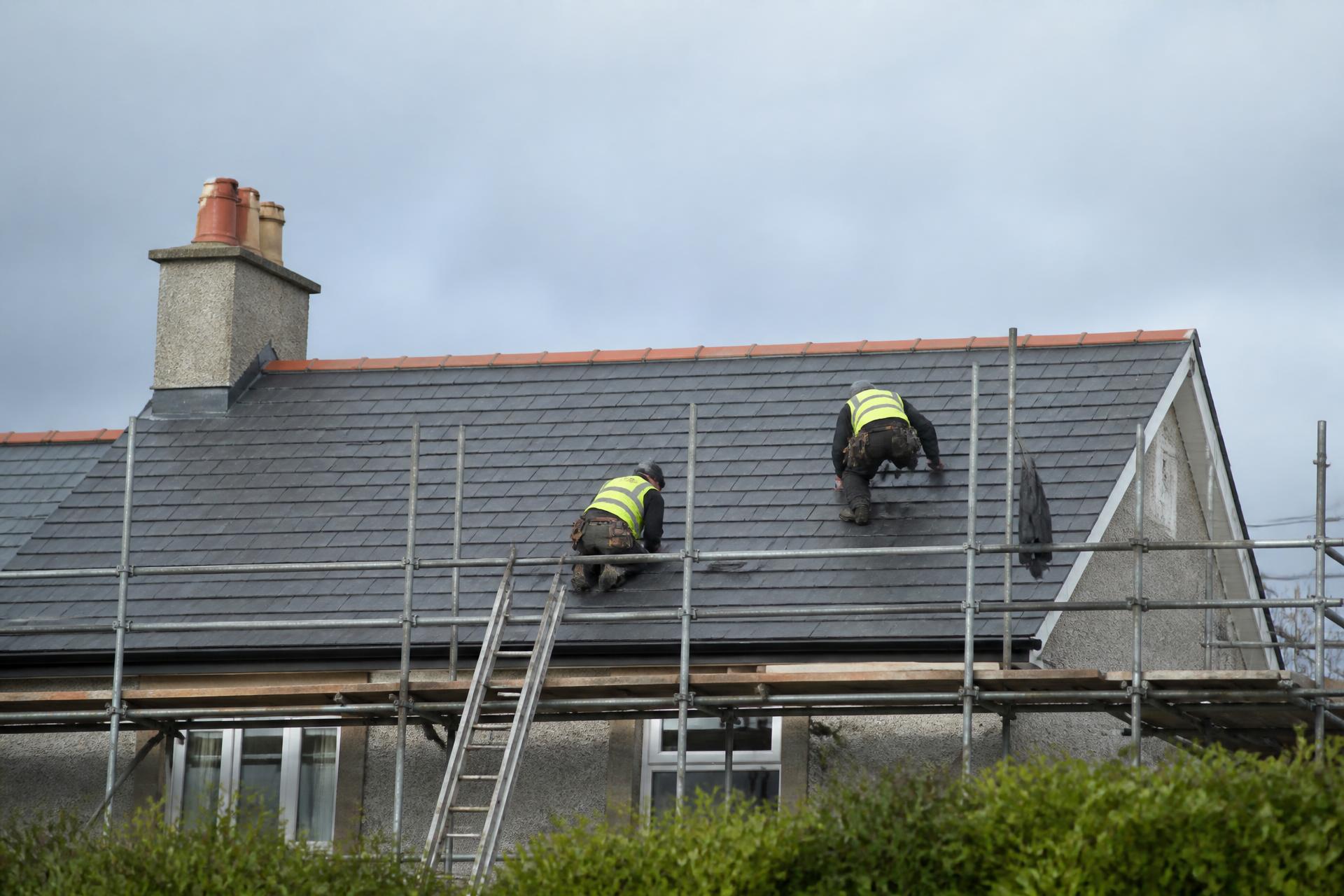 Professional roofers fitting slates on a residential roof in the Irish midlands